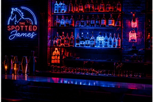The Spotted James bar back with neon sign and lit bottles