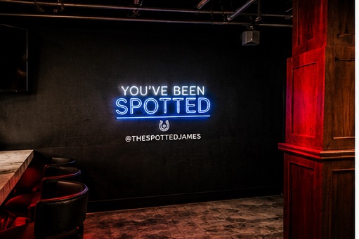The 'You've been spotted' neon sign on the wall