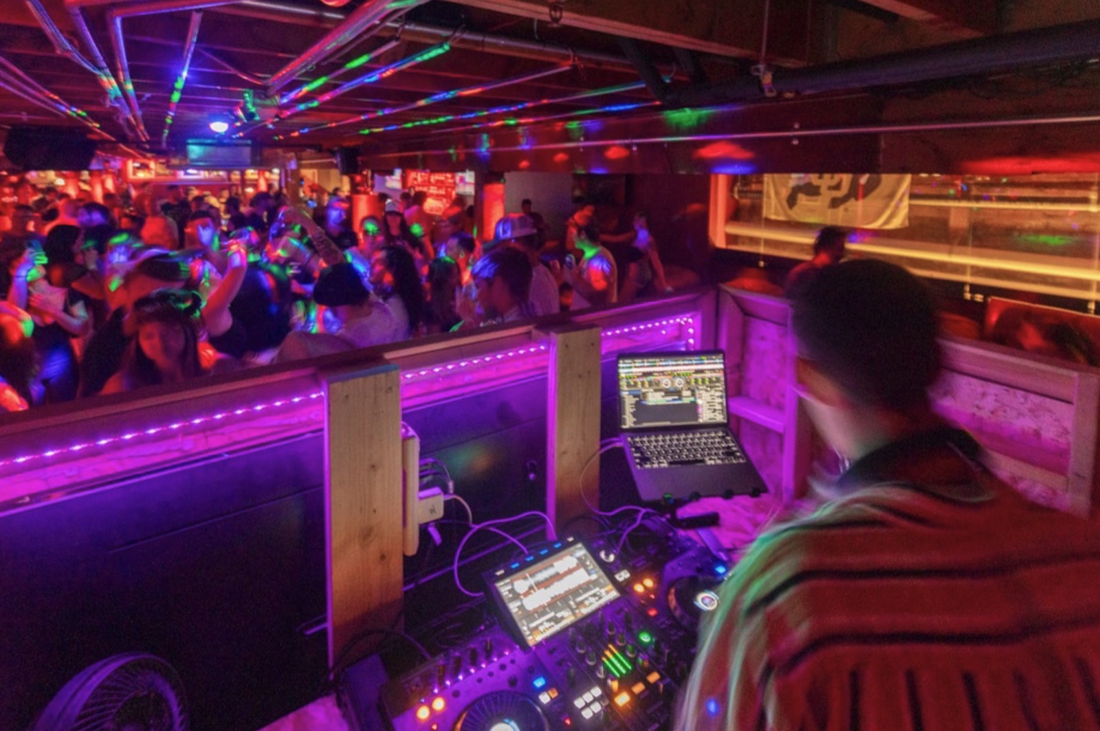 DJ playing to a packed, colorful dance floor at The Spotted James