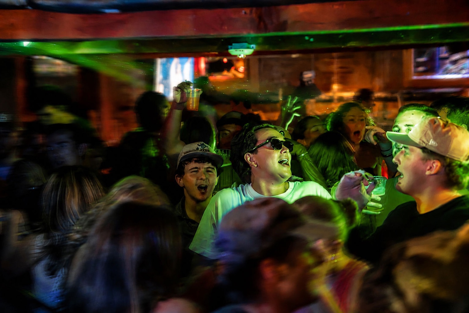 Crowd singing along under green stage lighting