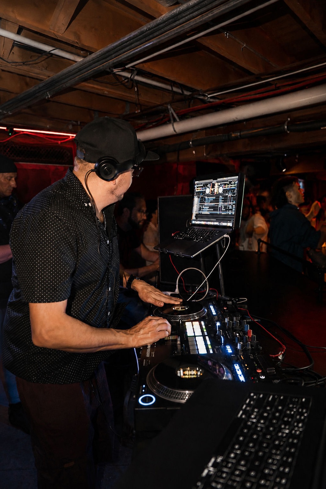 DJ working the decks and laptop during a late set