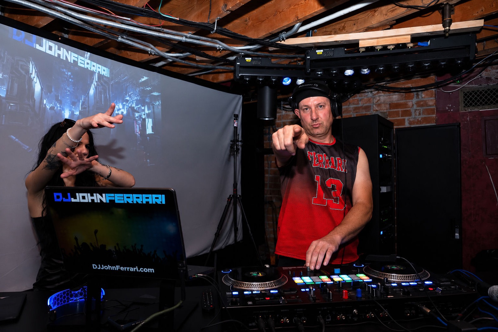 DJ John Ferrari pointing to the crowd from behind the decks