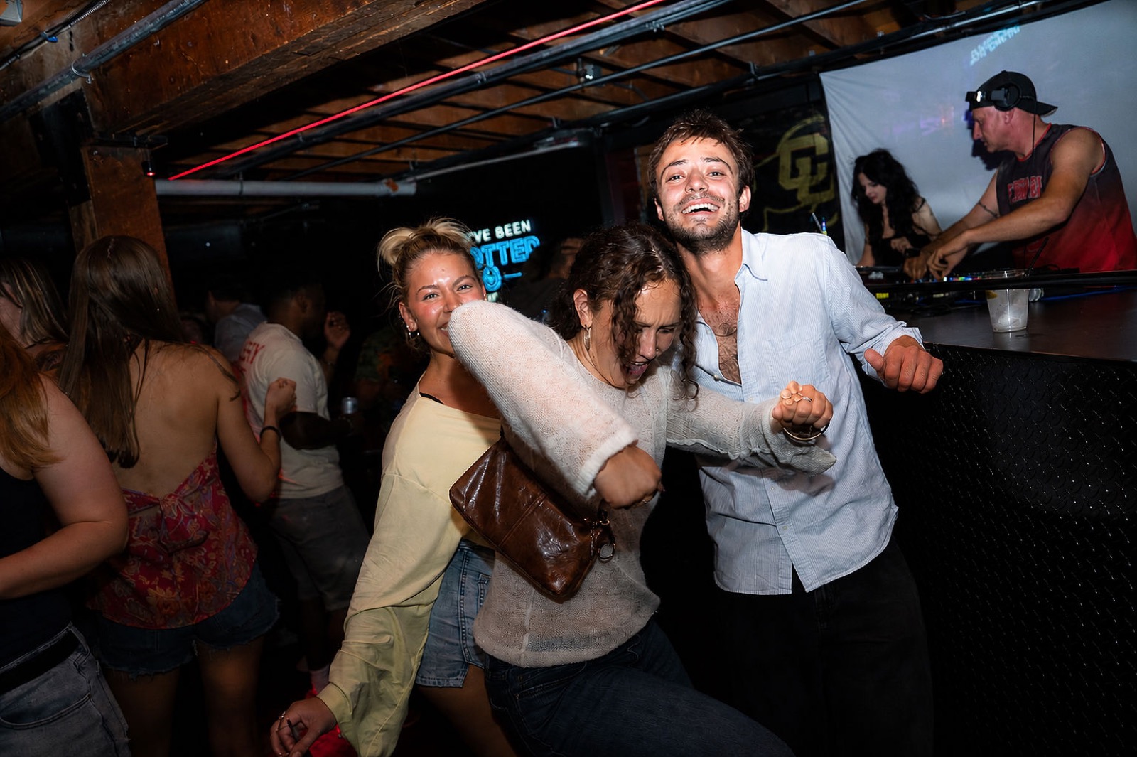 Friends laughing and dancing together near the DJ booth