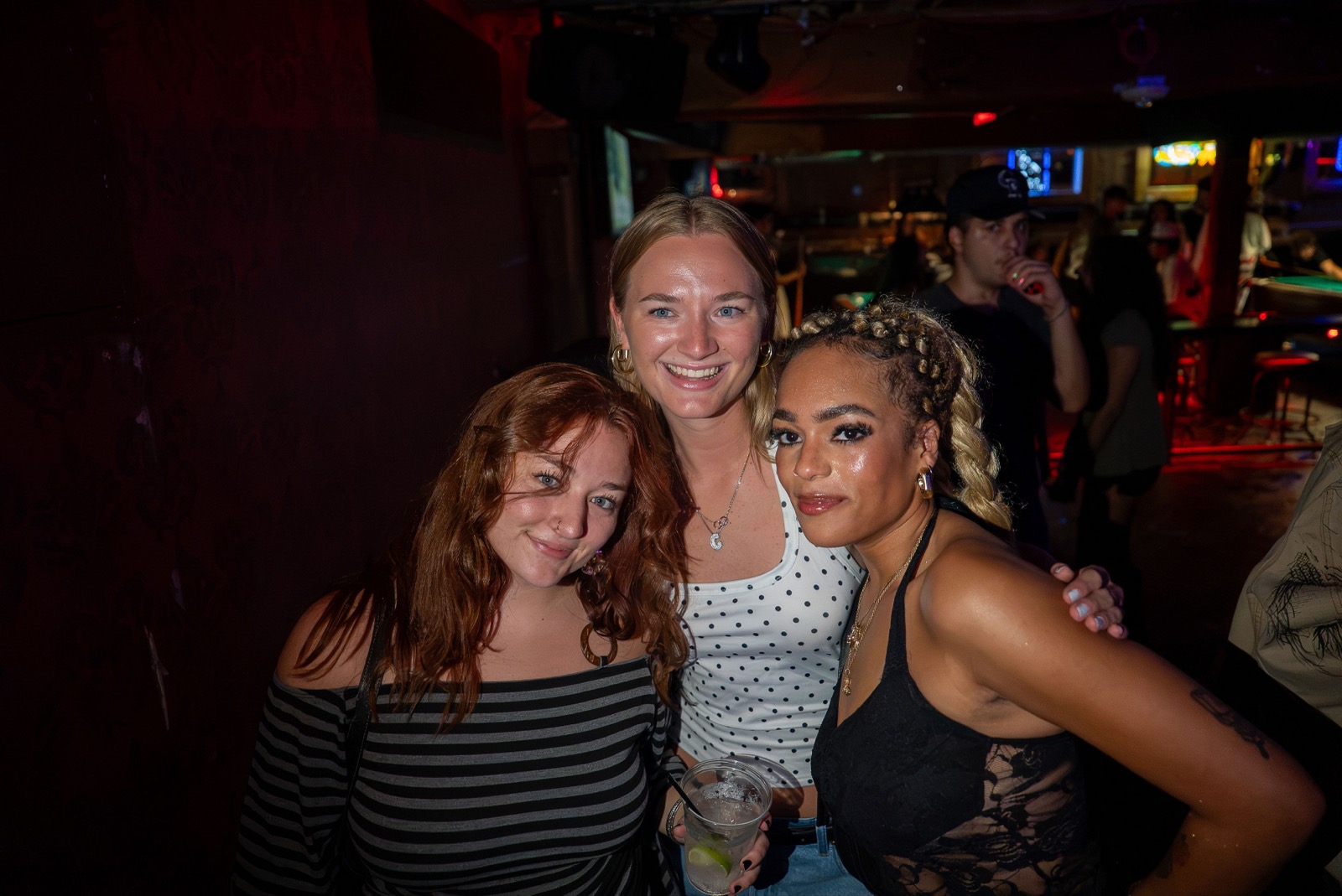 Three friends posing together with drinks at The Spotted James