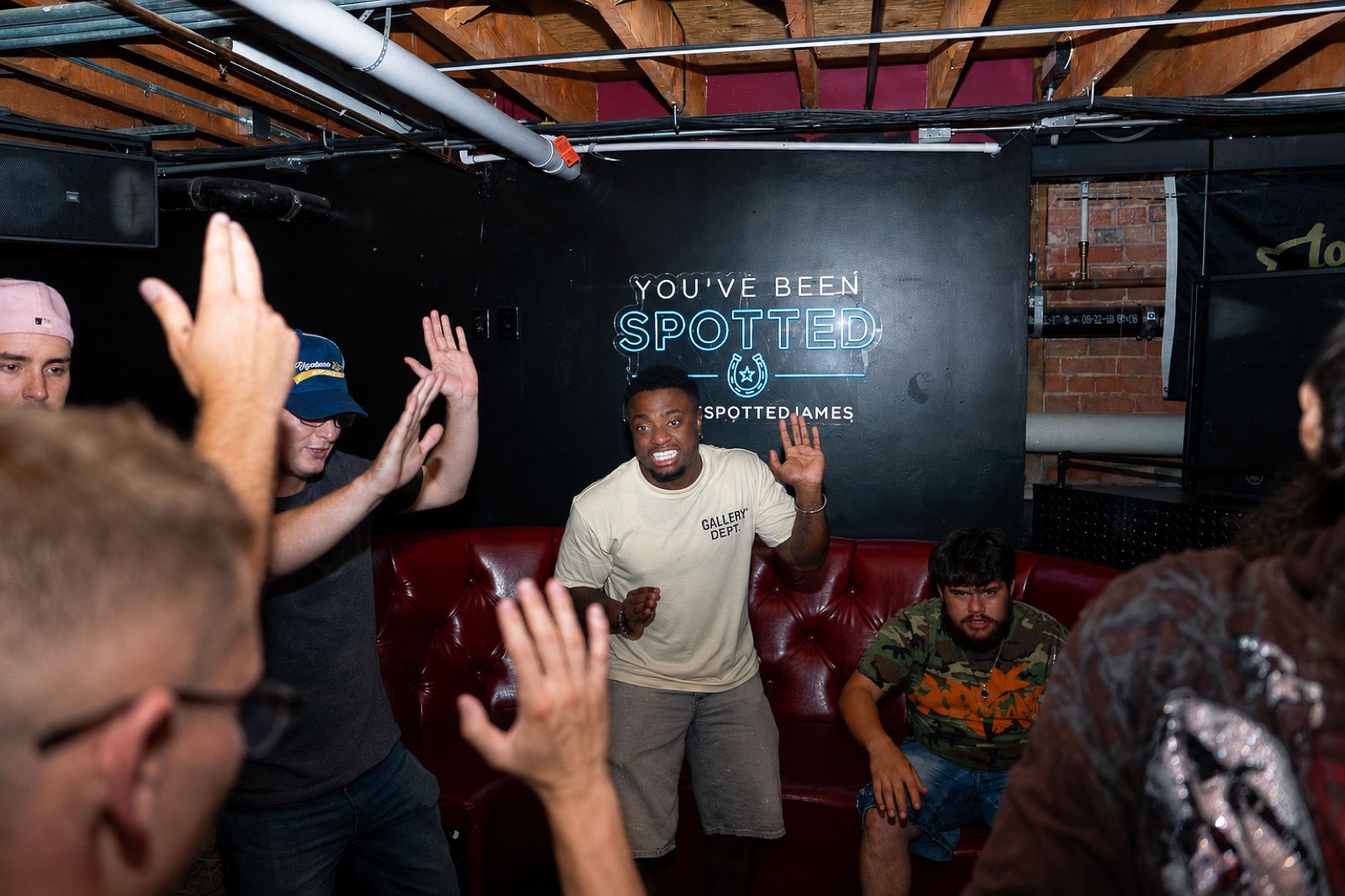Guests dancing in front of the You've Been Spotted neon sign