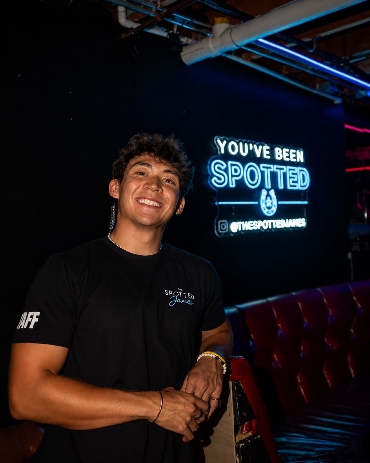 Spotted James staff member beside the You've Been Spotted neon sign